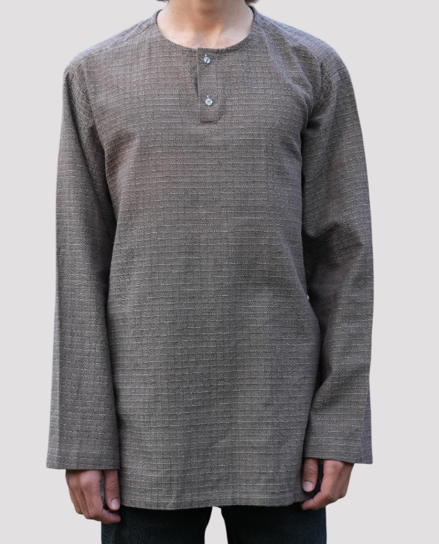 A man wearing a charcoal-colored Henley shirt with a textured pattern, long sleeves, and a two-button placket, offering a sleek and relaxed style.